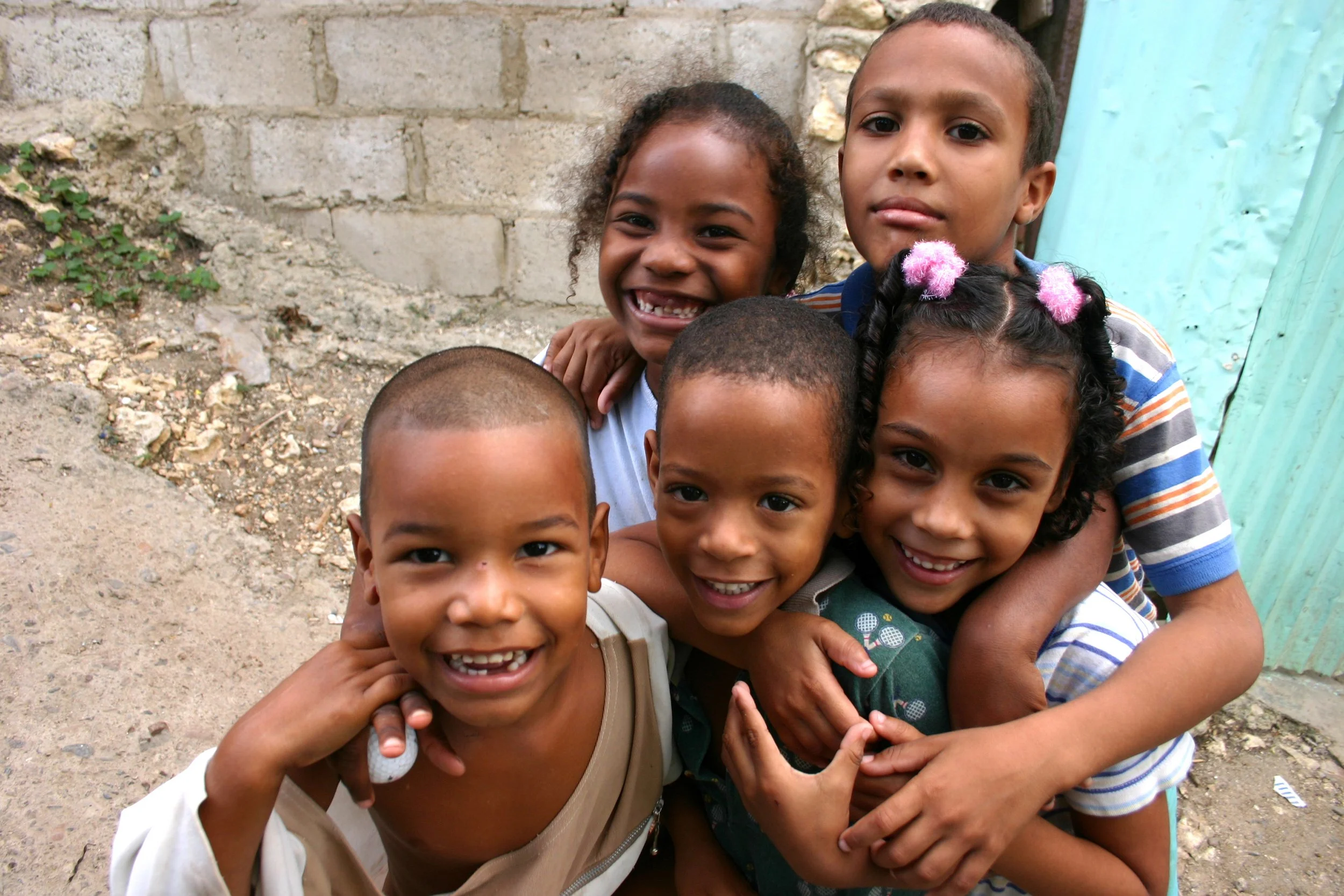 Groupe d'enfants souriants et heureux, regroupés de près, dans un environnement extérieur.