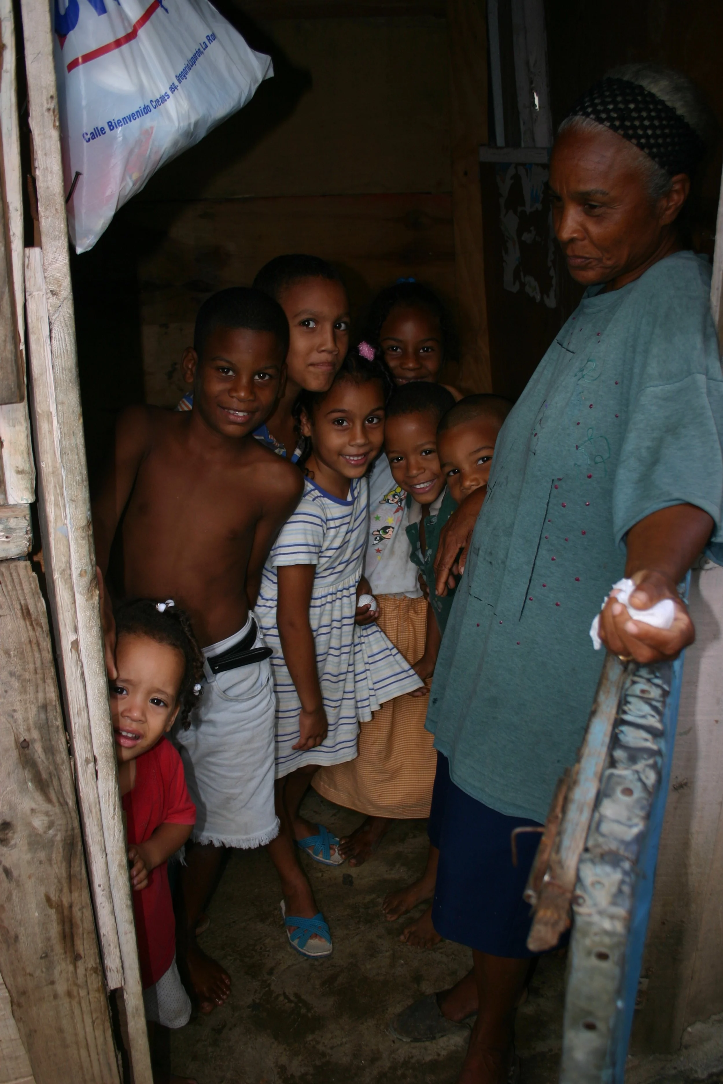 Une femme âgée entourée d'enfants souriants dans une pièce en bois