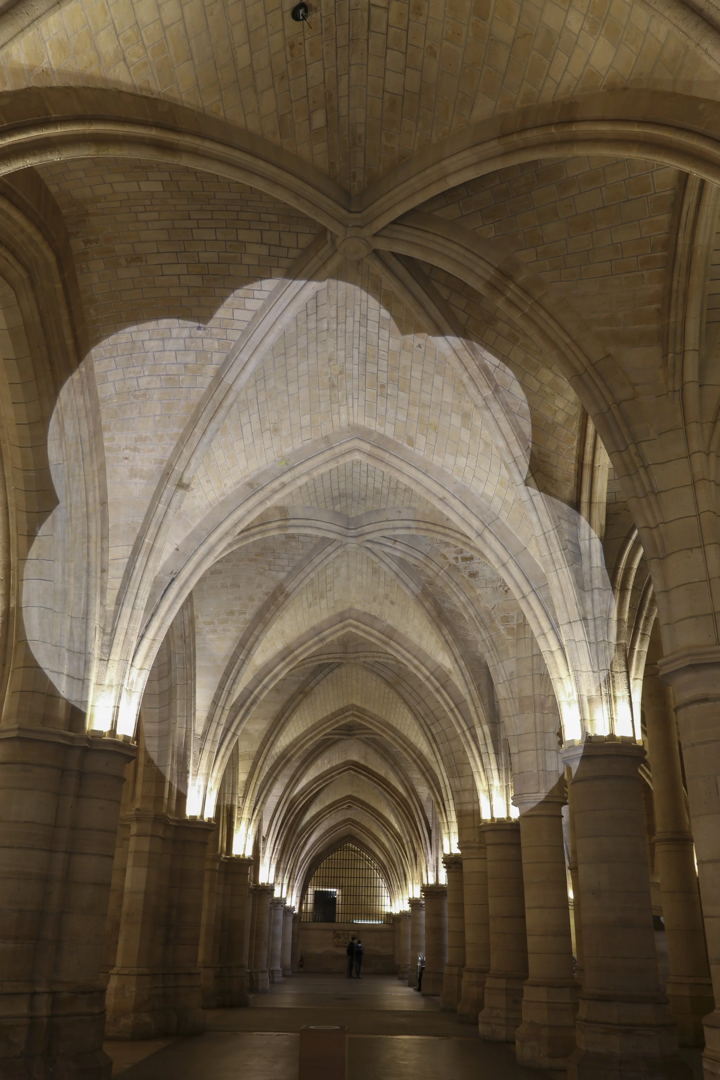 Intérieur d'une grande église ou cathédrale en pierre avec des arches gothiques, éclairée par des lumières discrètes.