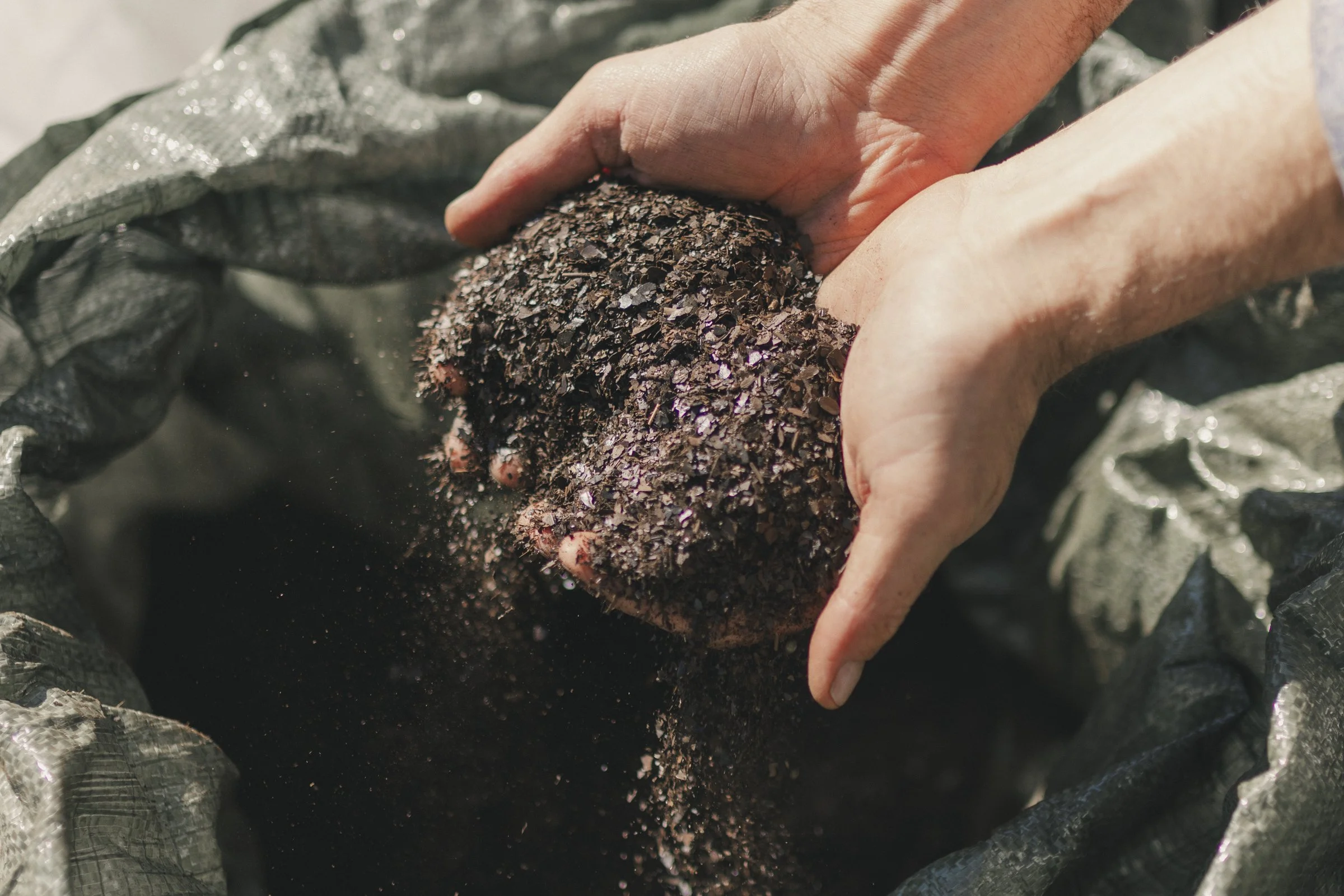 Modern wooden house in a grassy field overlooking a lake with mountains in the background during sunset.