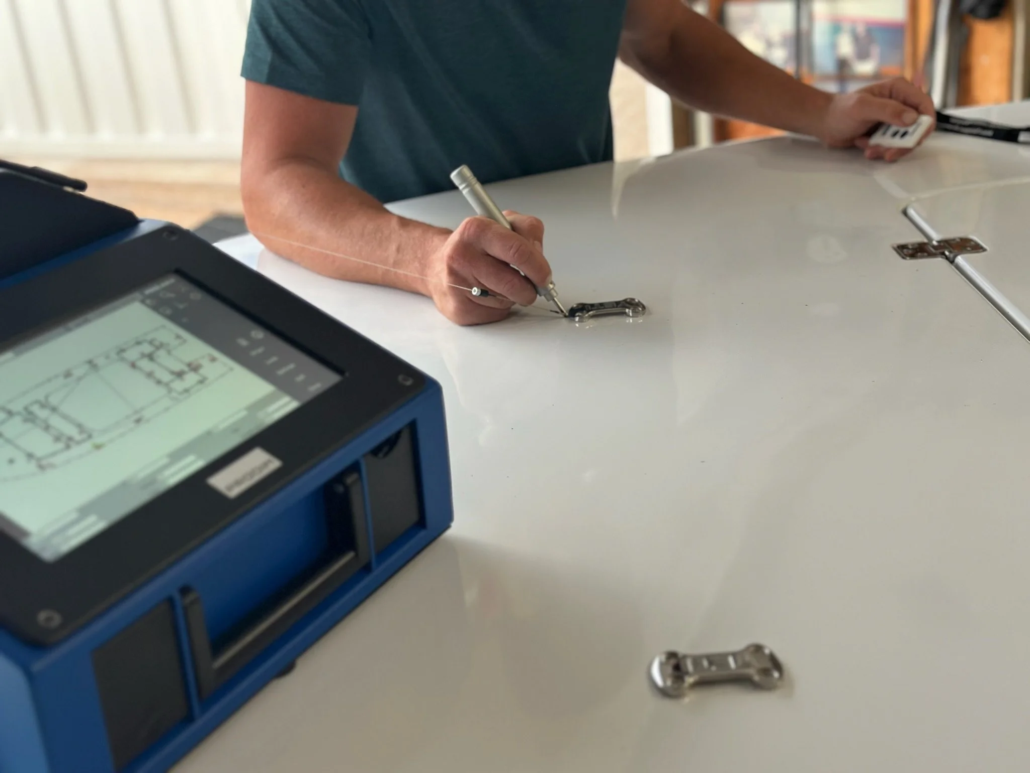 Person using a digital measuring device to trace and record the layout of a boat deck. The touchscreen unit and measuring tools capture precise dimensions for custom EVA/PE marine decking installation in South Florida.