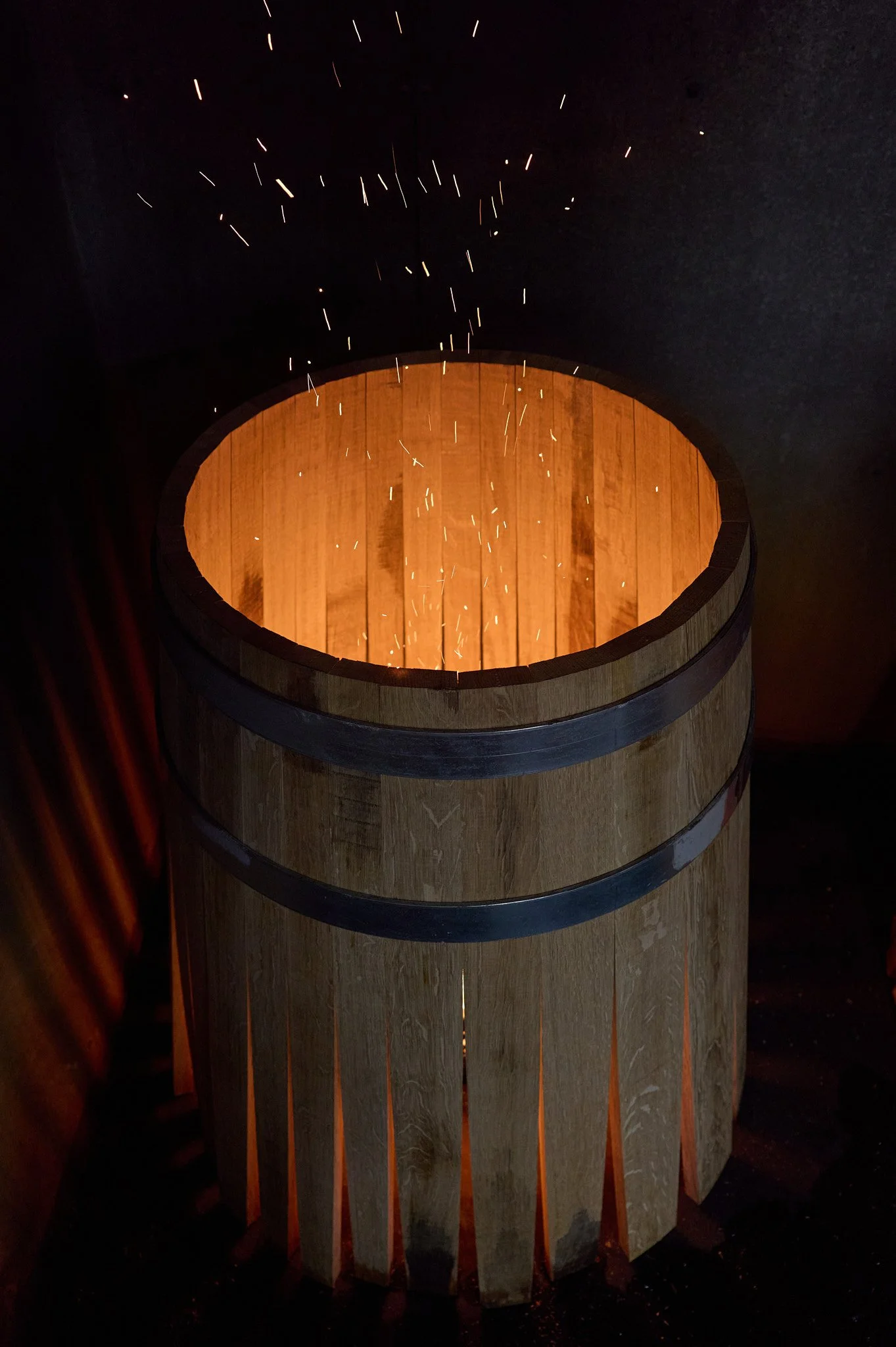Un tonneau en bois sans couverture, avec des étincelles sortant en haut.