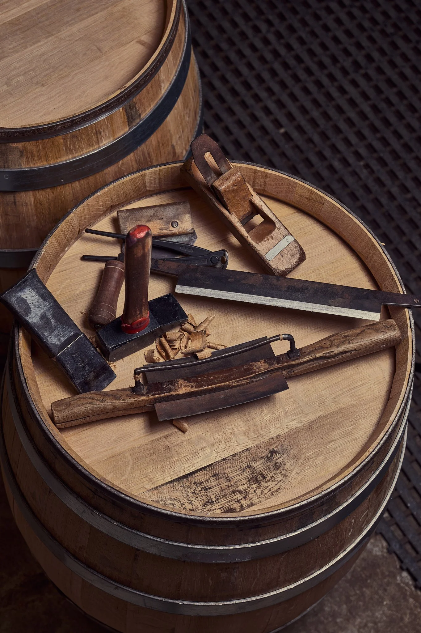 Dessus d'un tonneau barrique en bois, avec plusieurs outils du tonnelier en bois et en métal posés dessus.