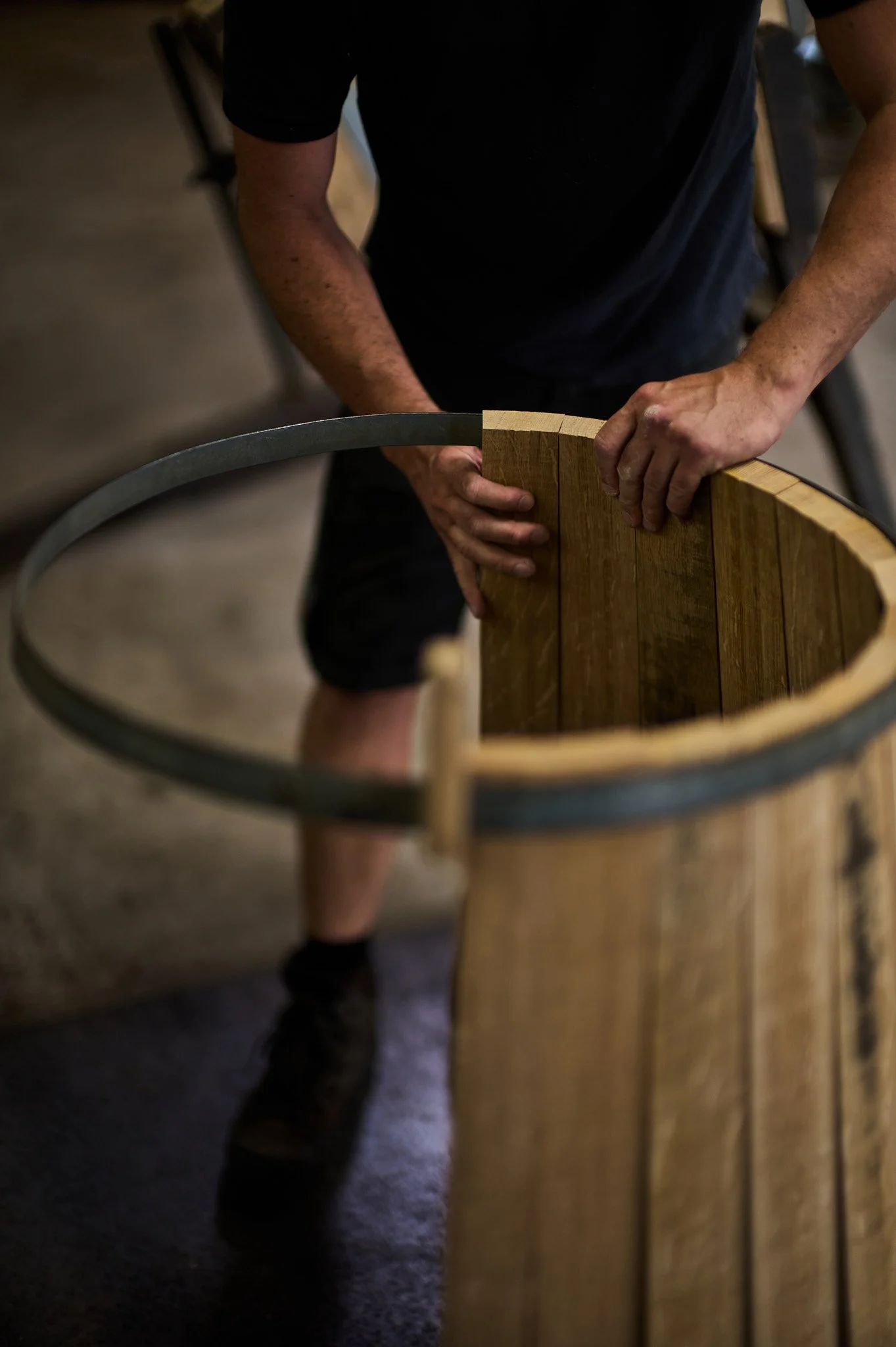 Un tonnelier en train de monter une barrique en bois.