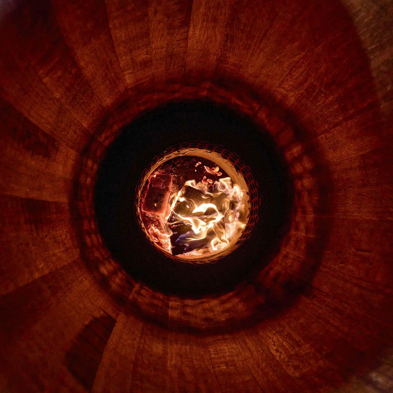 Feu dans un conteneur circulaire en métal, éclairé par la flamme.