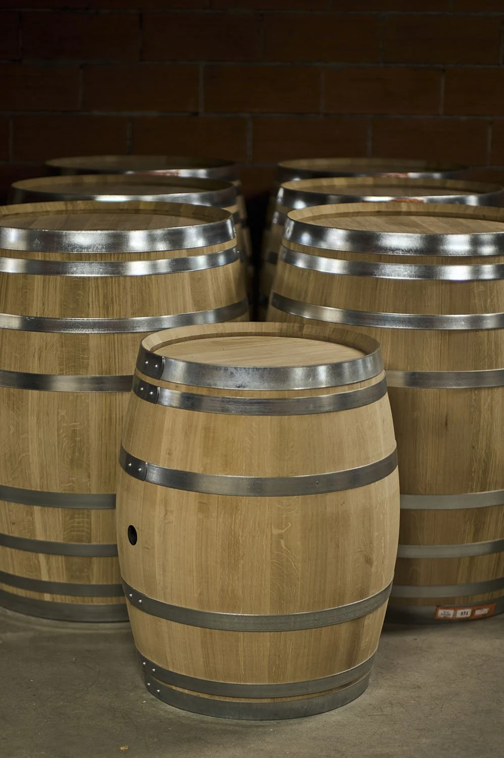 Tonneaux en bois empilés, utilisés pour le stockage de vin ou de whisky, dans une cave ou un entrepôt.