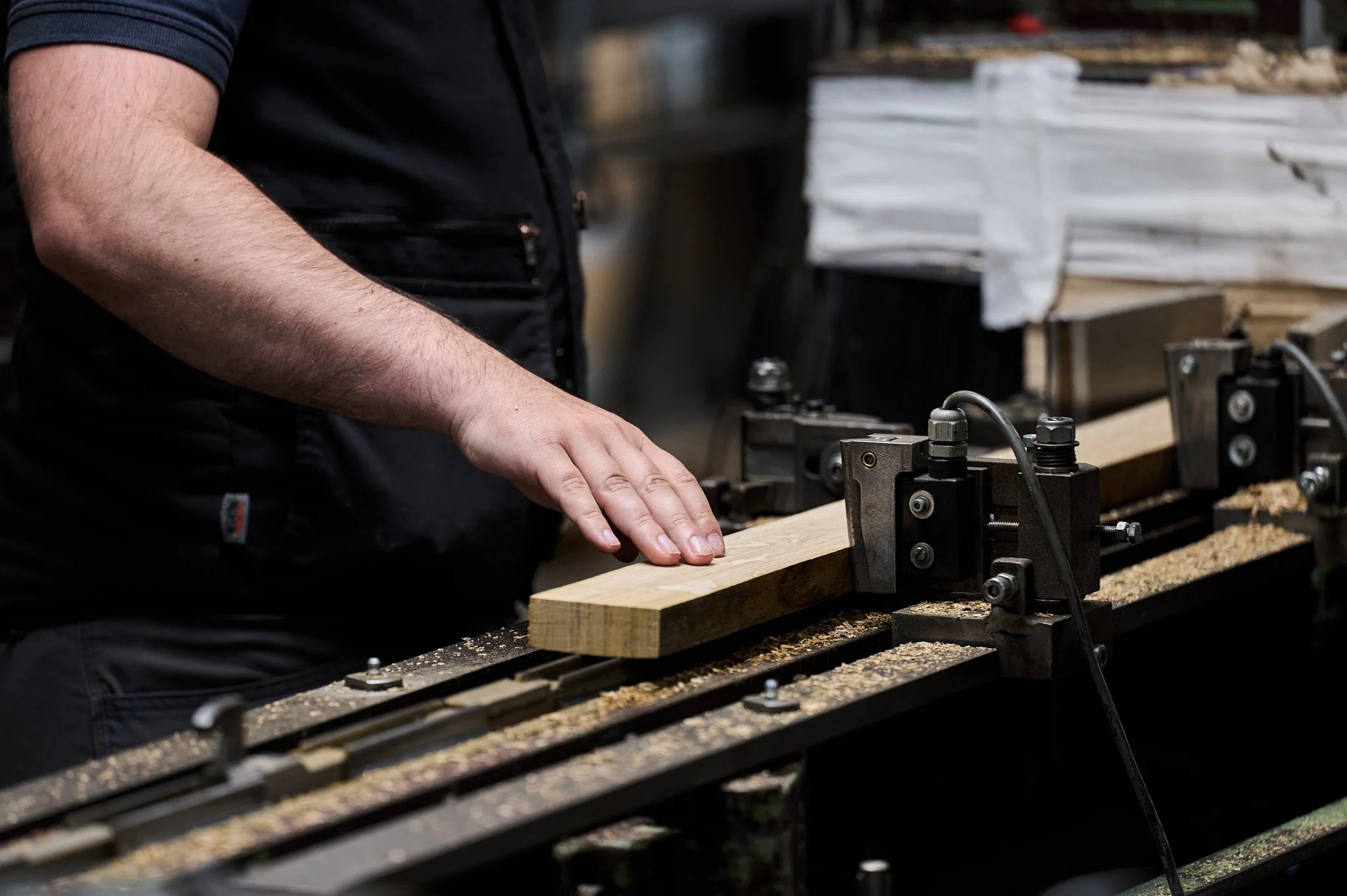 Un homme utilisant une machine à bois pour couper ou façonner une pièce de bois dans un atelier.