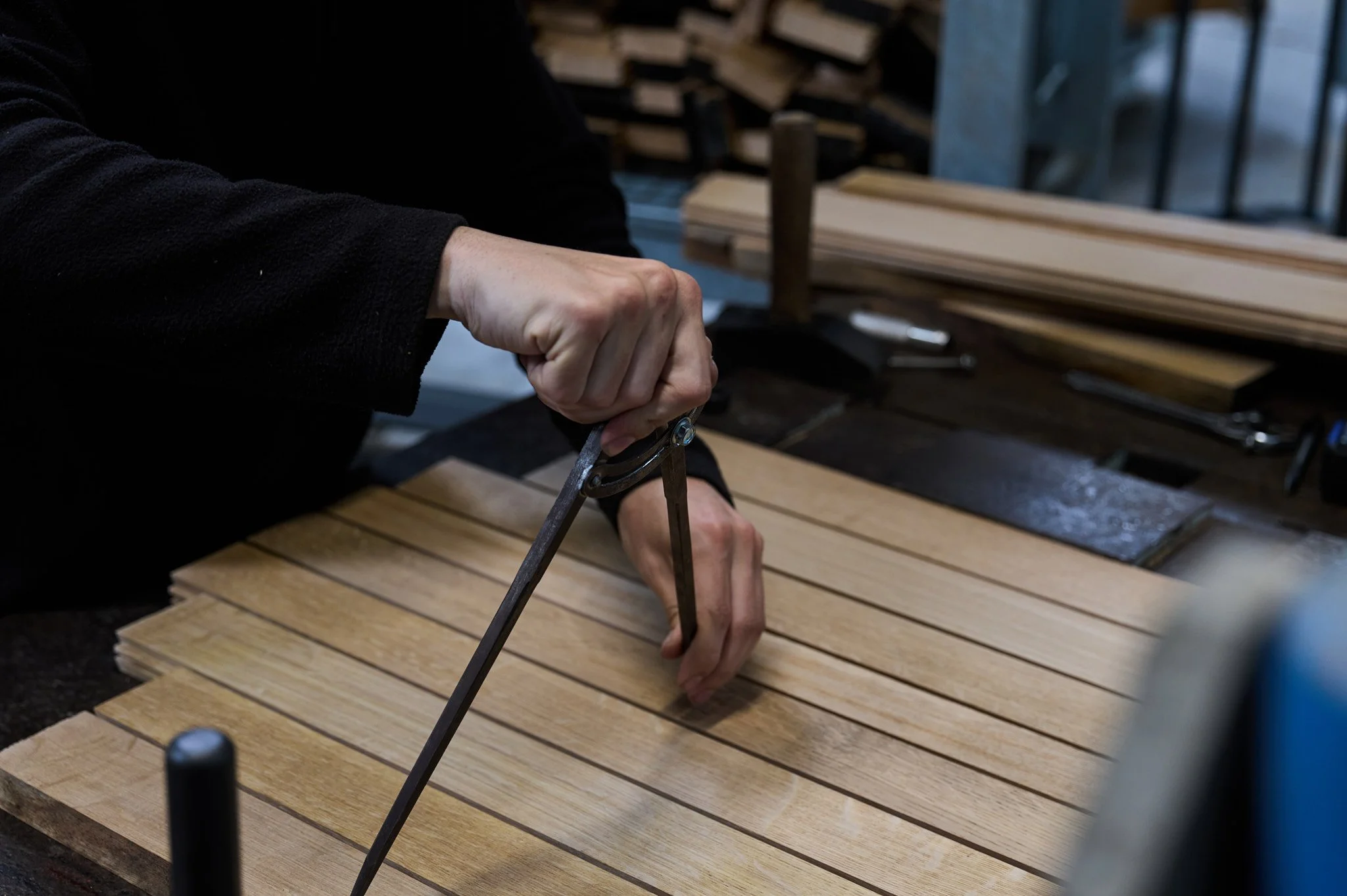 Main de l'artisan tonnelier utilisant un compas pour dessiner la découpe du montage du fond de la barrique en bois.
