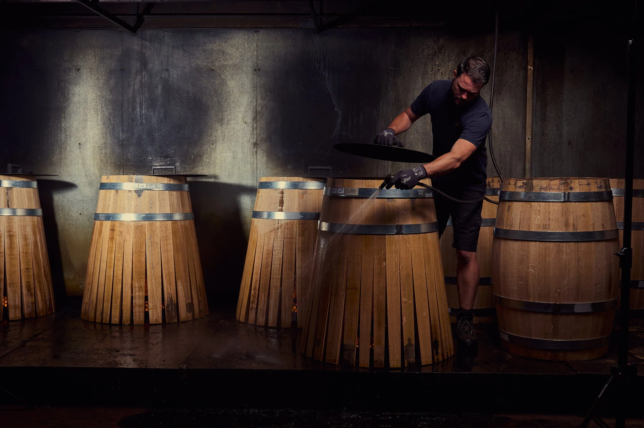 Un homme artisan tonnelier qui façonne une barrique en bois.