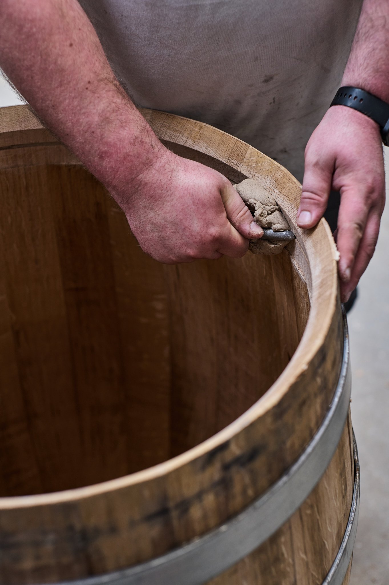 Une personne utilisant un couteau pour faire du travail du bois sur un tonneau en bois.