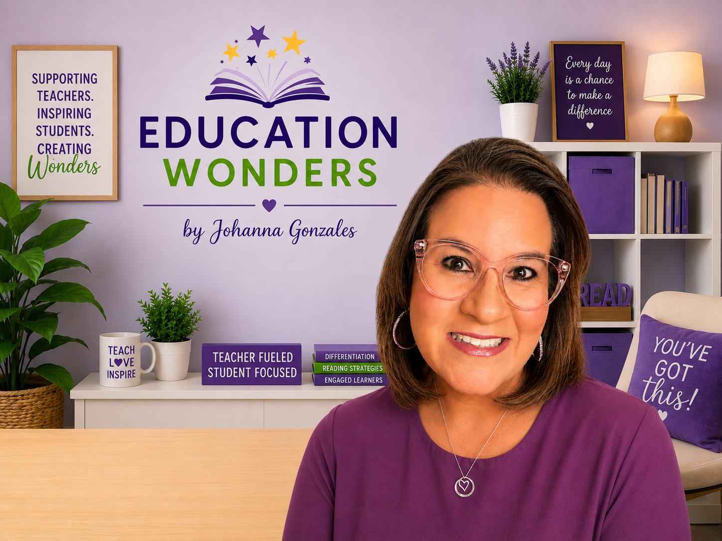 A woman wearing glasses and a purple top smiling in a colorful classroom with educational decorations and bookshelves.