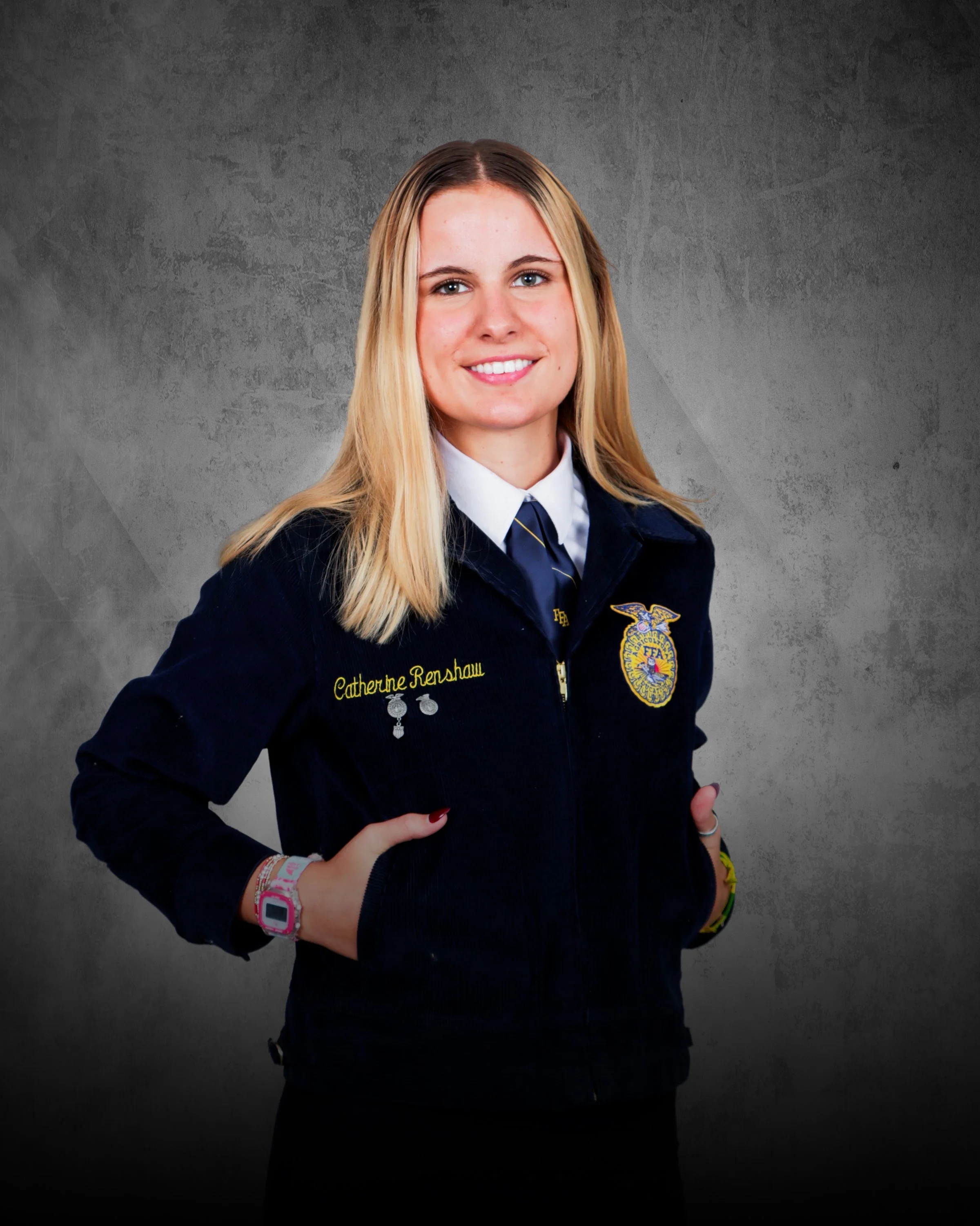 Smiling young woman with long blonde hair in a black school uniform standing outside at an event.