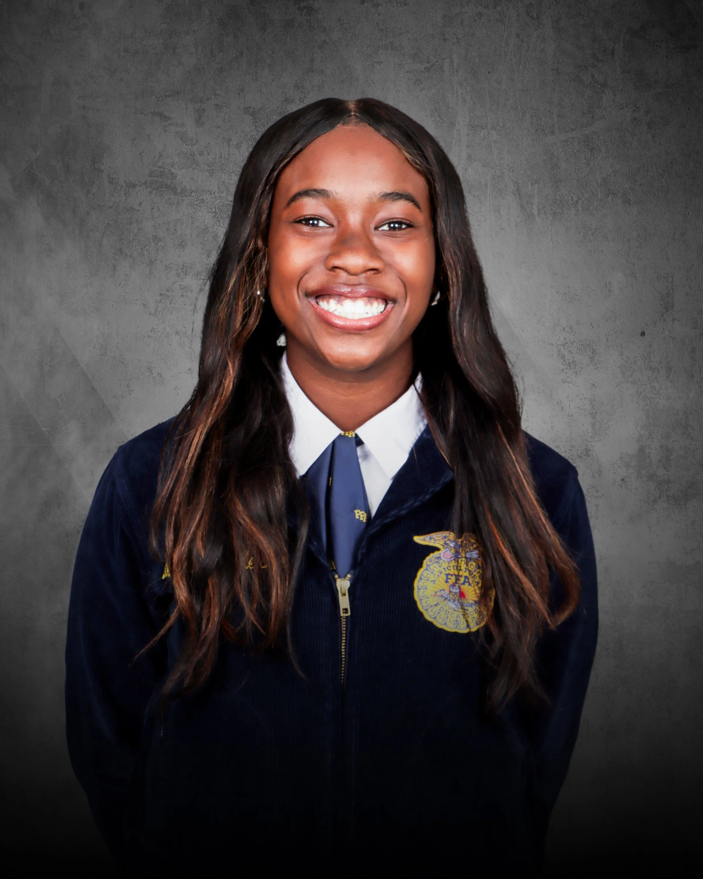 A woman with curly hair, glasses, and earrings smiling indoors.