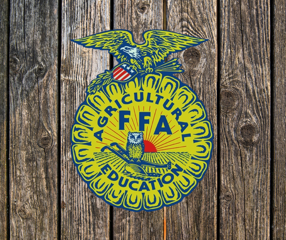 Emblem of the FFA (Future Farmers of America) with an eagle, owl, and sunrise design against a wooden background.