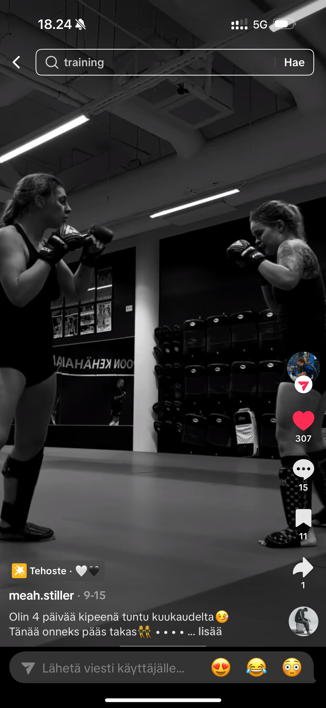 Kuvassa kaksi naista taistelee nyrkkeilyssä salin sisällä, toinen vasemmalla ja toinen oikealla. Taustalla on tasasivuinen hylly käsipainoille, ja seinällä näkyy peili ja osittain teksti 'ON KENHÄÄLIA'.