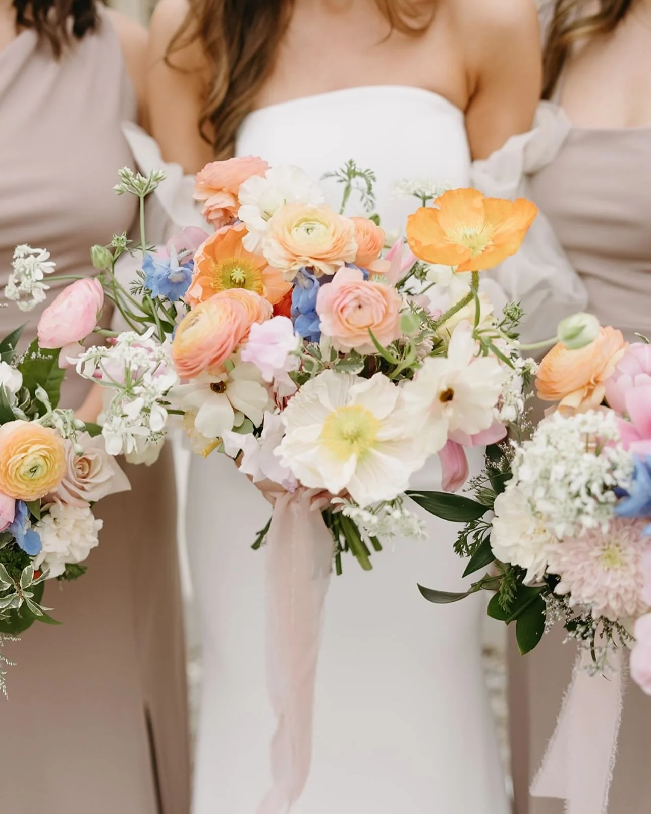 Close-up of a bride holding a colorful bouquet of flowers at a wedding.