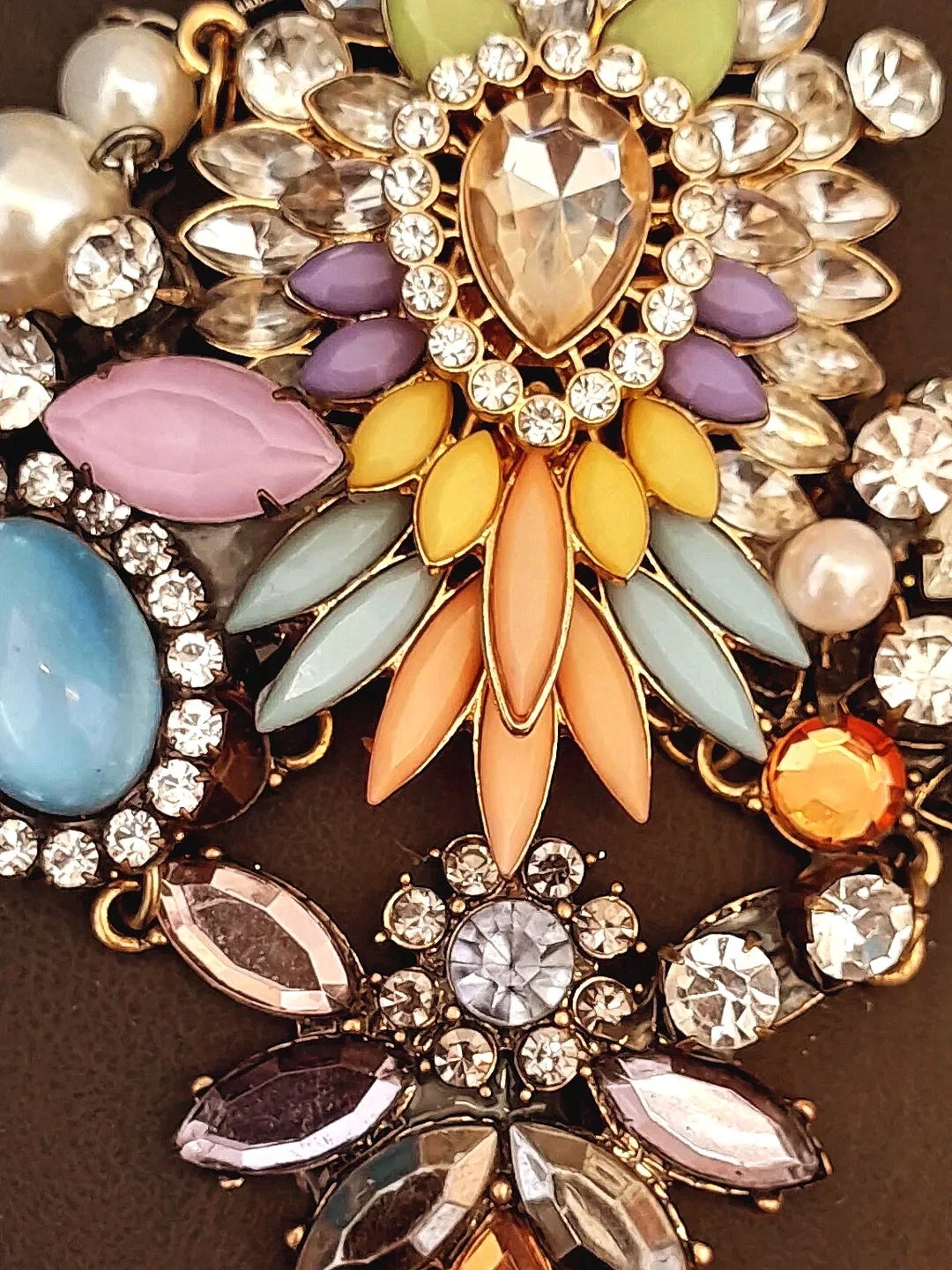 Close-up of a colorful decorative brooch with various pastel and jewel-tone stones and rhinestones.