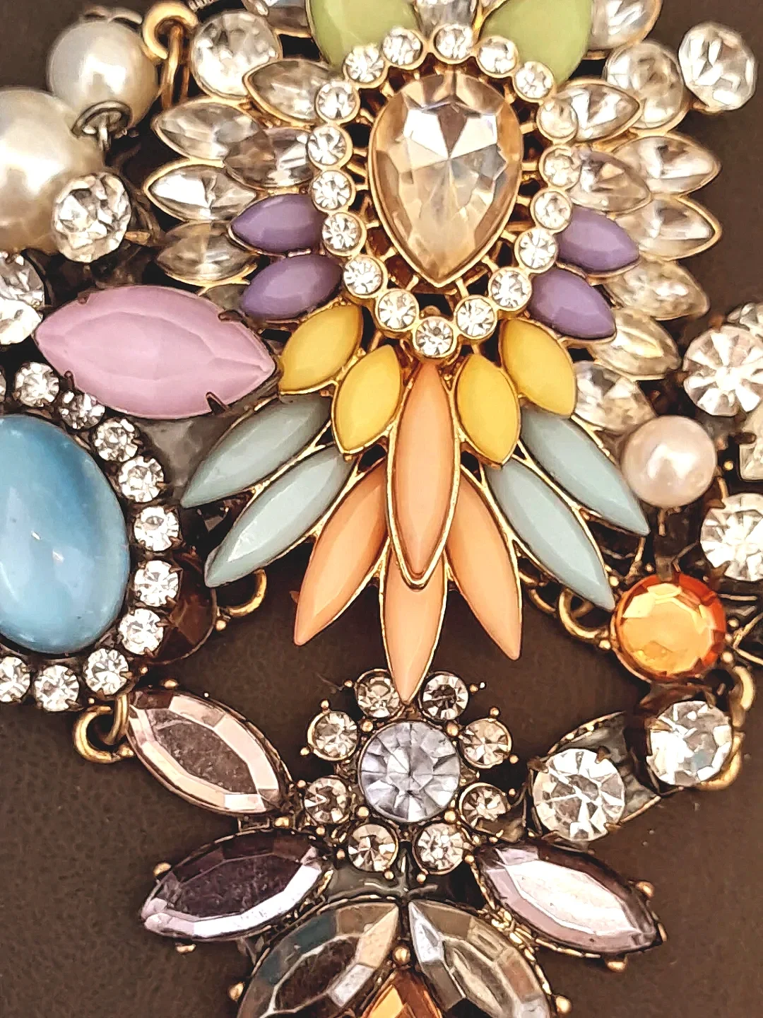 Close-up of colorful, floral and jewel-tone necklace with rhinestones, pearls, and pastel-colored stones.