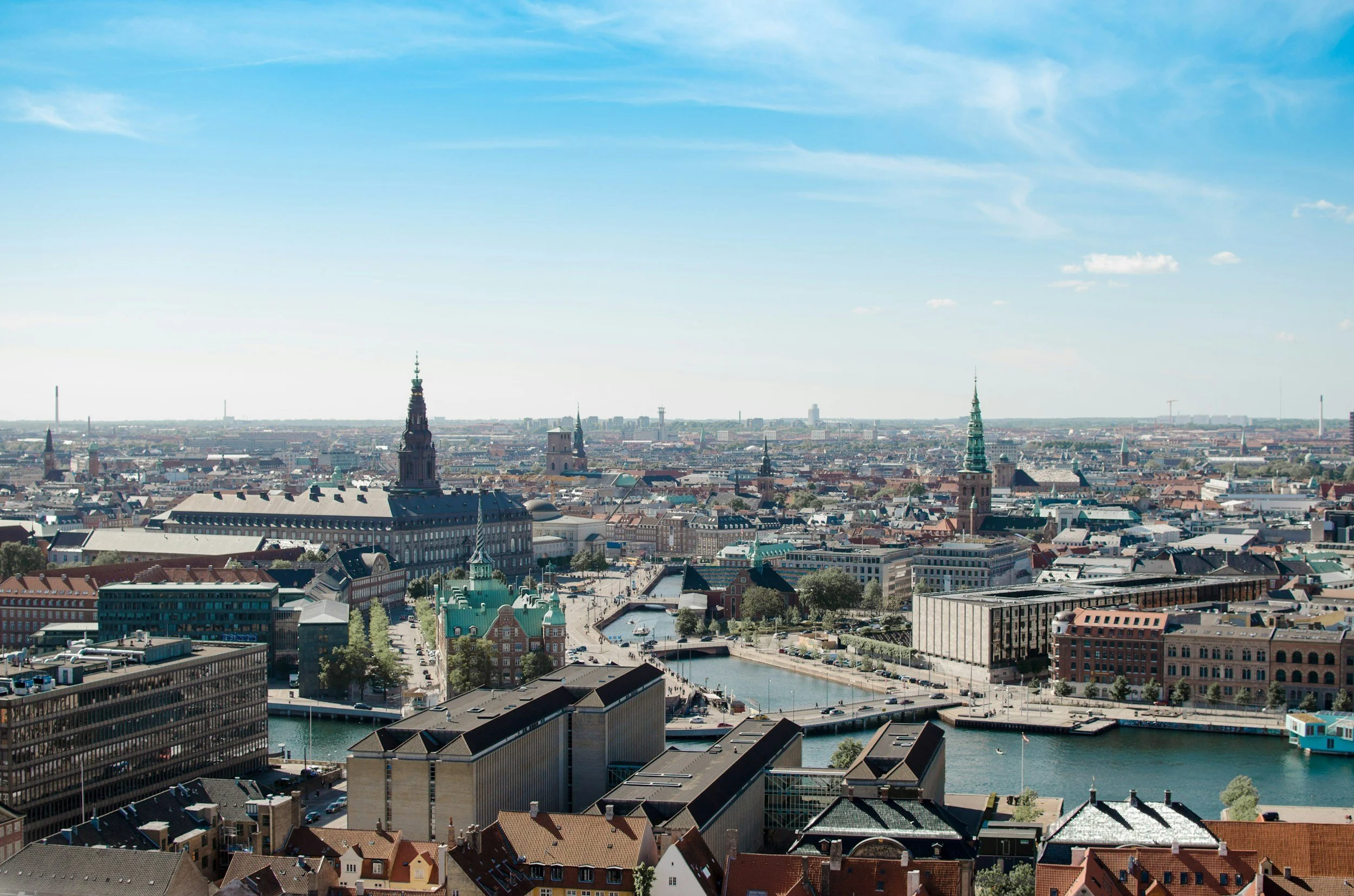 A panoramic view of a cityscape with historic buildings, a river, and a clear blue sky.