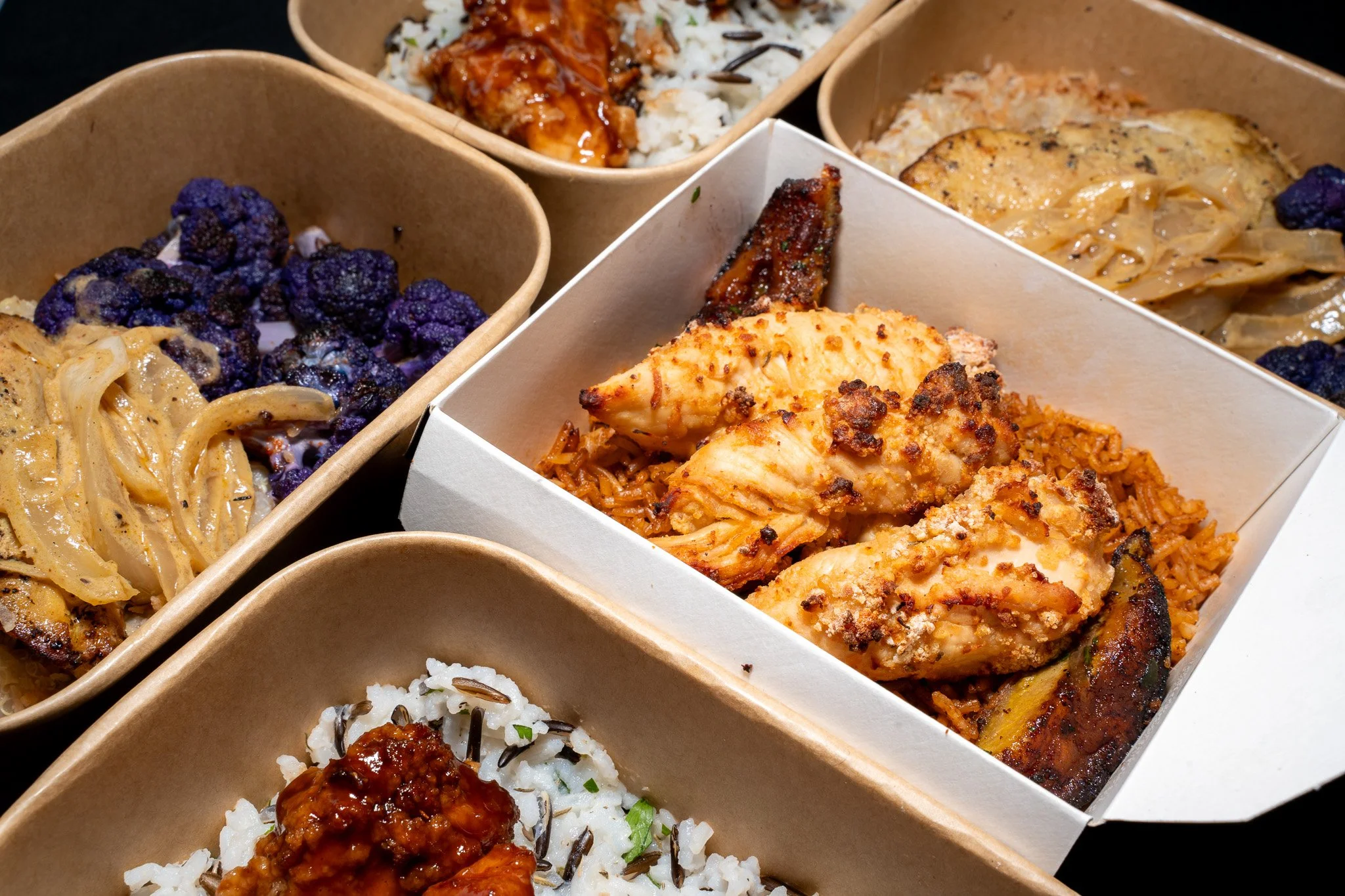 Assorted Asian-style dumplings, rice, and vegetables in takeout containers.