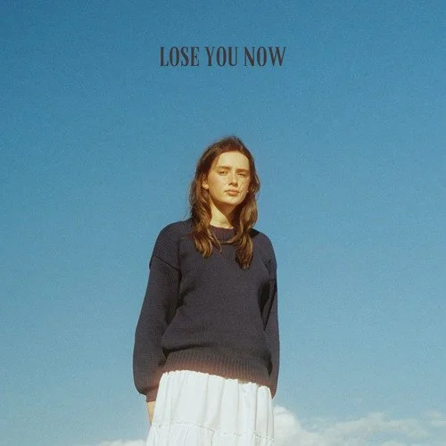 Person standing outdoors under a clear blue sky with the words "LOSE YOU NOW" written above their head.