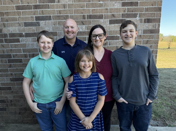 Shannan and her family standing in front of a brick wall and smiling