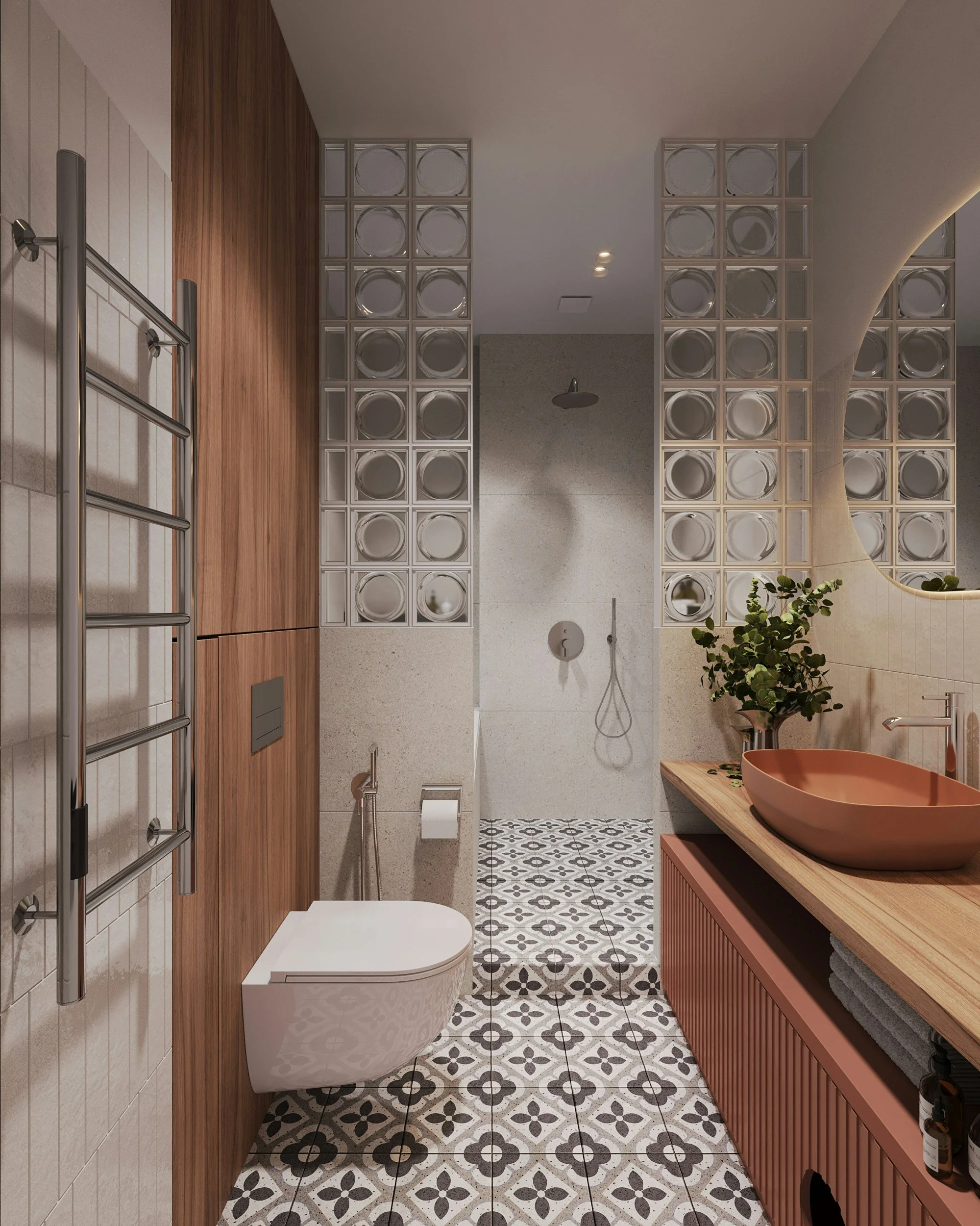 Bagno con piastrelle decorative nere e bianche, lavabo rotondo in terracotta su un mobile in legno e grande specchio circolare, area doccia con soffitto piatto e piastrelle di colore chiaro, scopino e bidet con tubo flessibile, asciugamani grigi, pianta verde nel mobile e termoscaldina in acciaio.