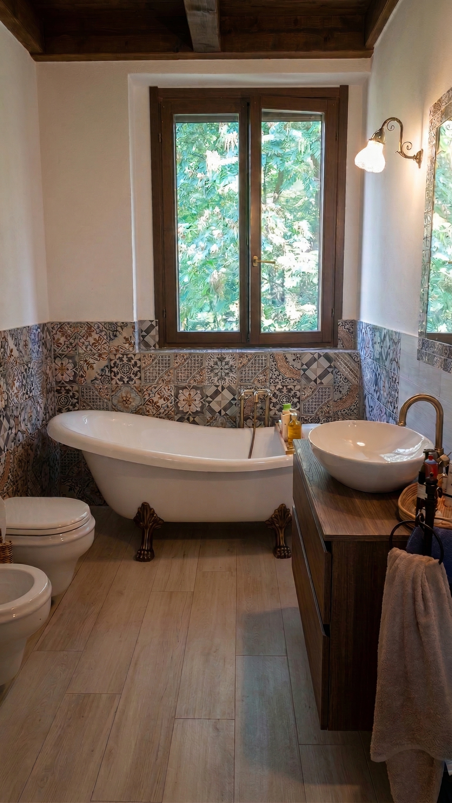 Bagno con vasca da bagno, lavabo in ciotola sopra mobile in legno, specchio, WC e bidet, finestra con vetri verdi, pareti con piastrelle decorative e pavimento in piastrelle beige.