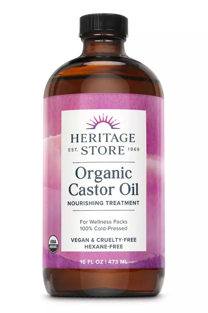 A brown bottle of Heritage Store organic castor oil with a purple and white label.