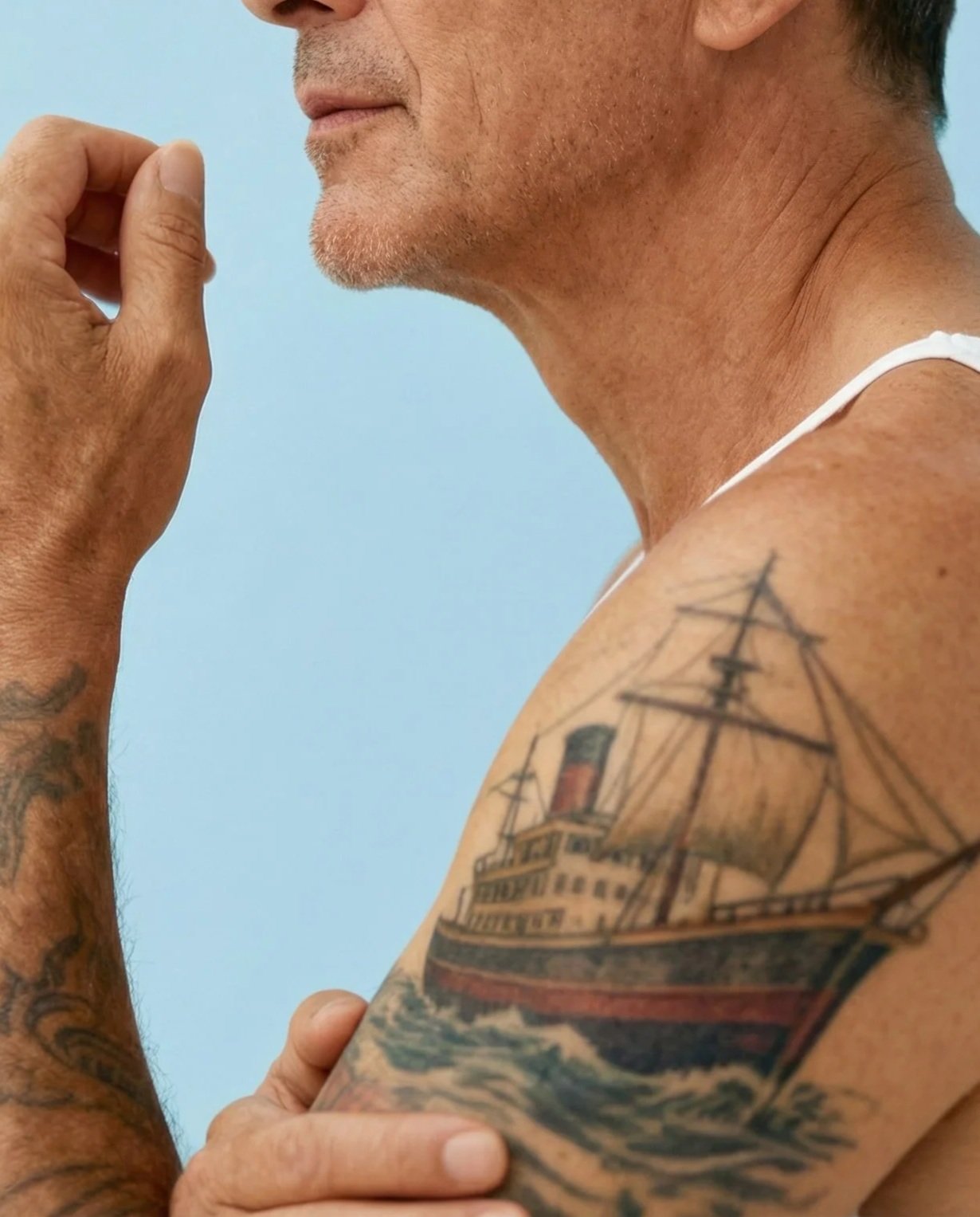 Un homme avec une tatouage d'un vieux navire sur son bras.