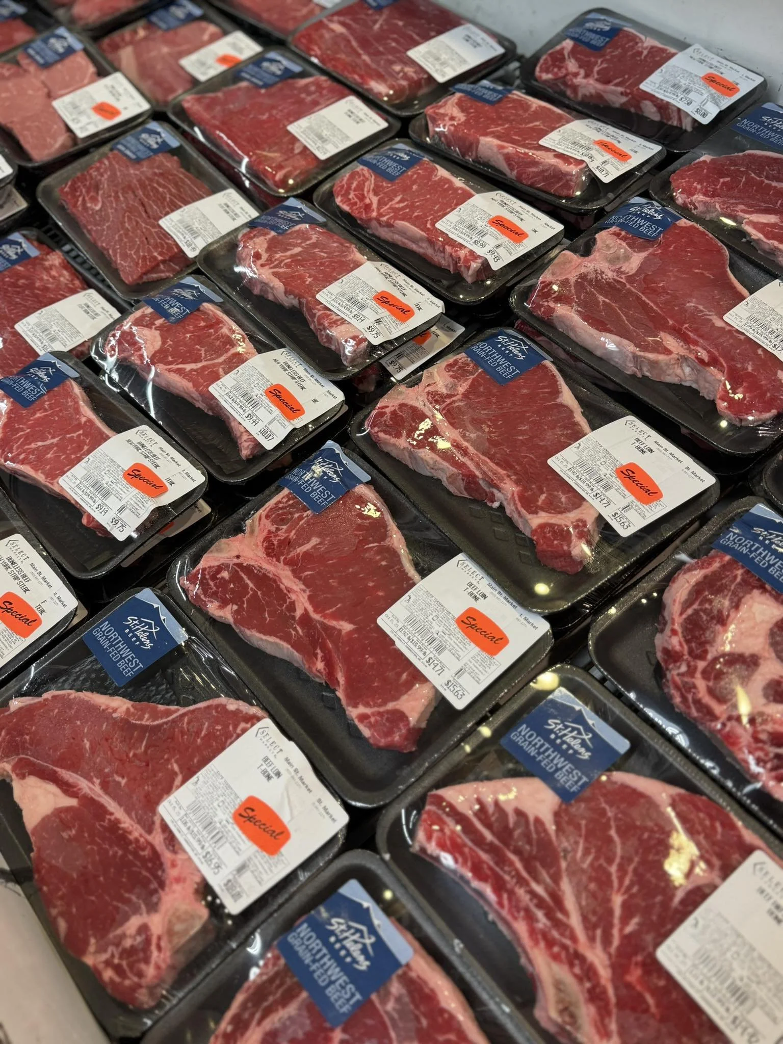 Several packages of fresh beef steak on display in a grocery store, labeled with price tags and expiration dates.