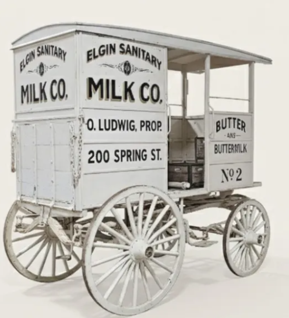 Vintage milk delivery wagon with signs for Elgin Sanitary Milk Co., Butter, and Buttermilk.
