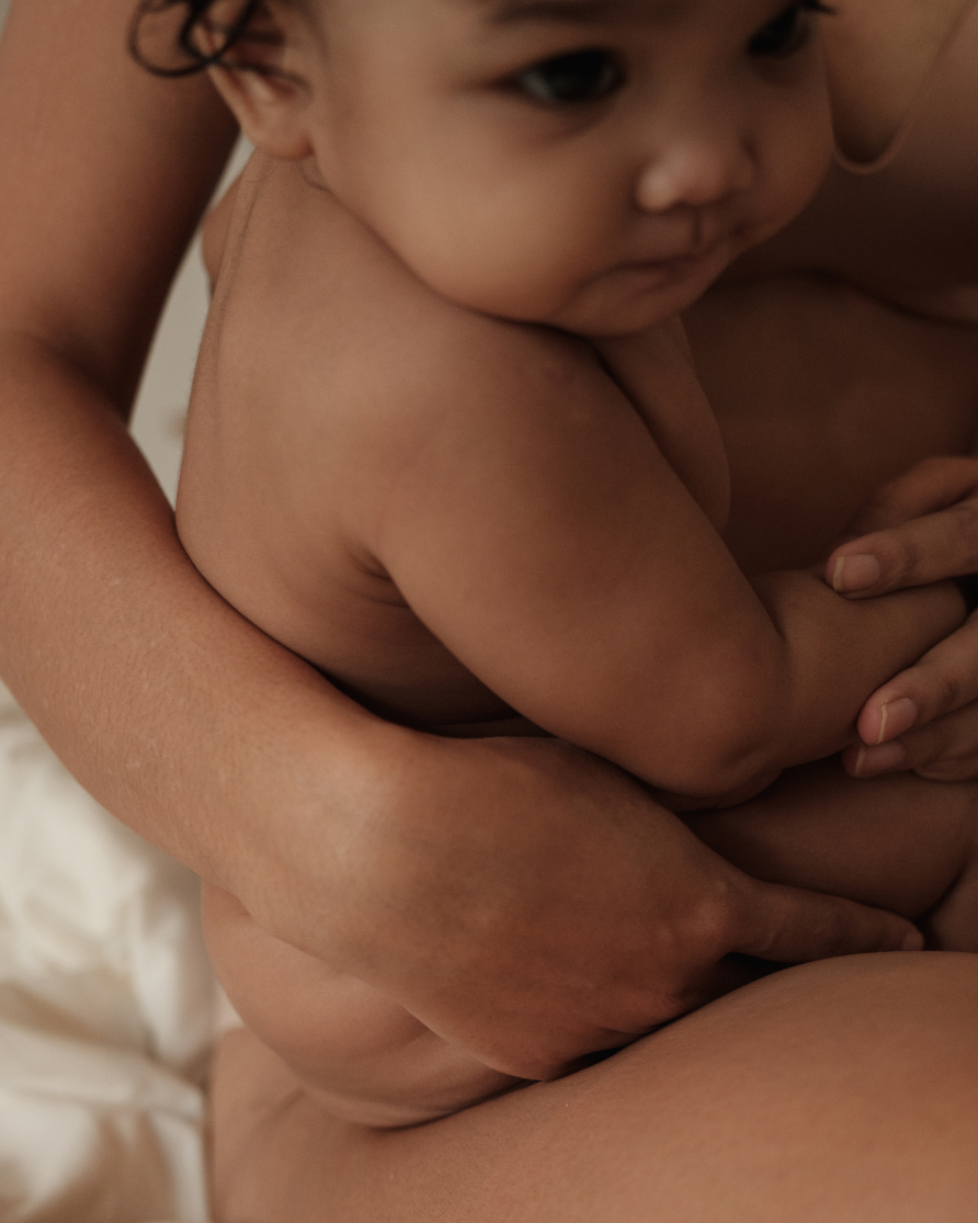 Close-up of a young child with dark hair, being held in an adult's arms.