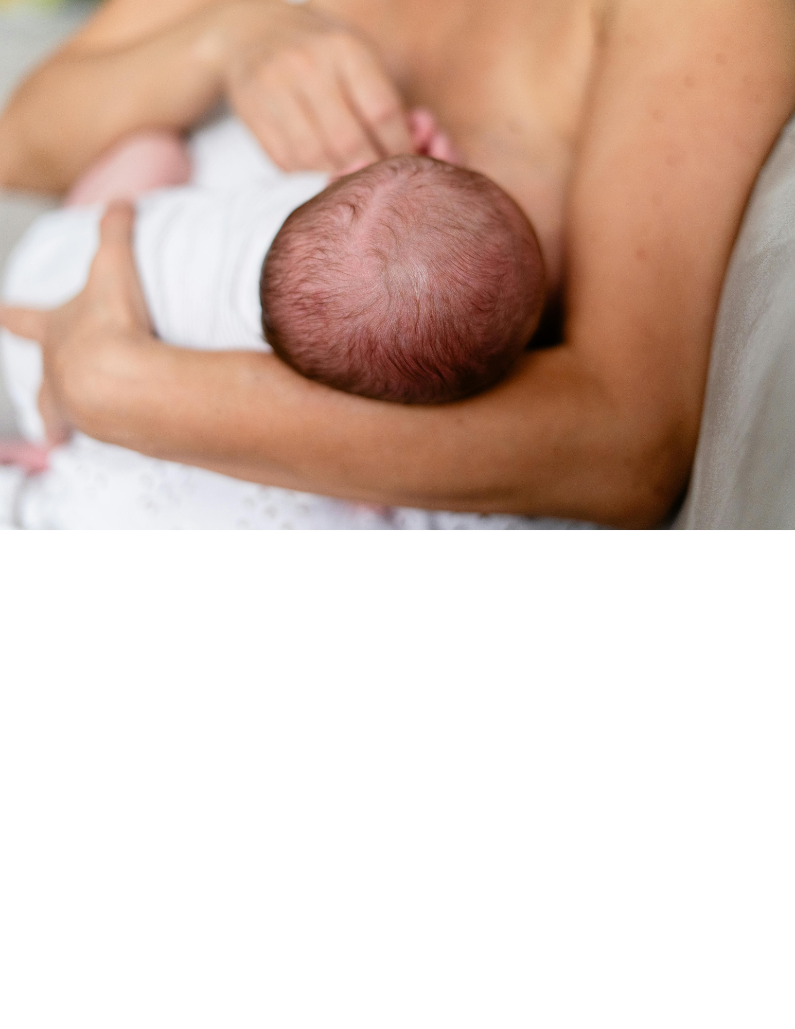 Close-up of a newborn baby breastfed by a mother.