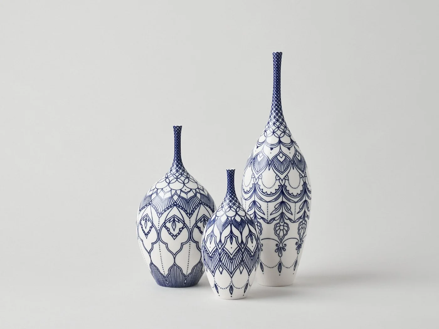 Three decorative vases with blue and white intricate patterns on a light gray background.