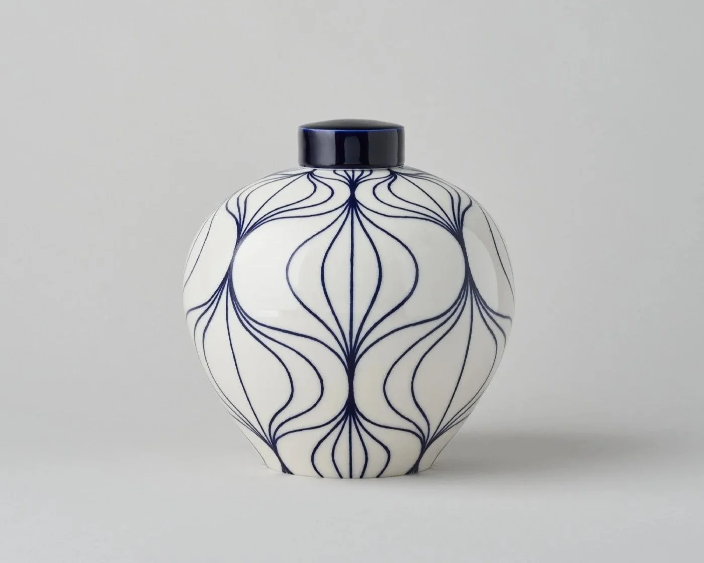 A white ceramic vase with blue line patterns and a black lid.