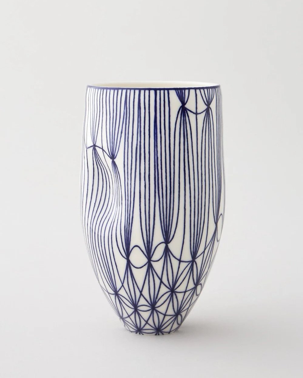 White ceramic vase with blue line art design resembling abstract floral and geometric patterns.