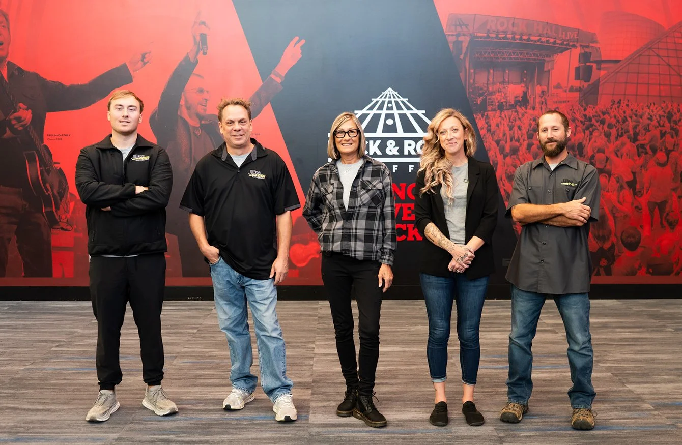 Team members standing in front of a large wall at the Rock & Roll Hall of Fame.