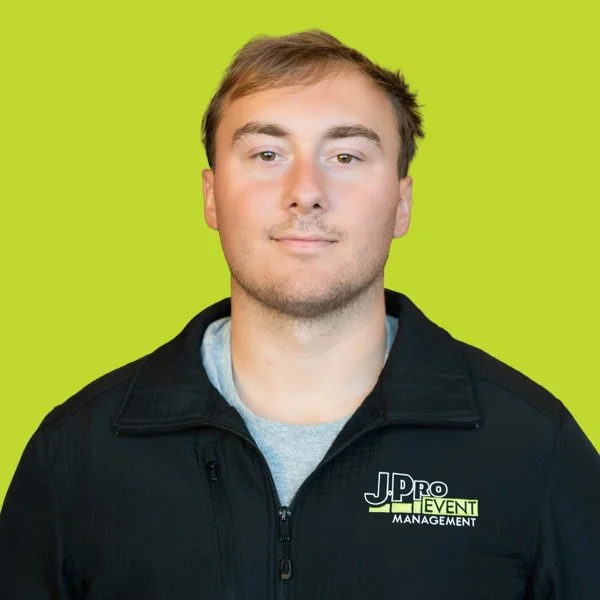 A young man in a black shirt with a logo that reads "J.Pro Event Management" stands against a bright green background.