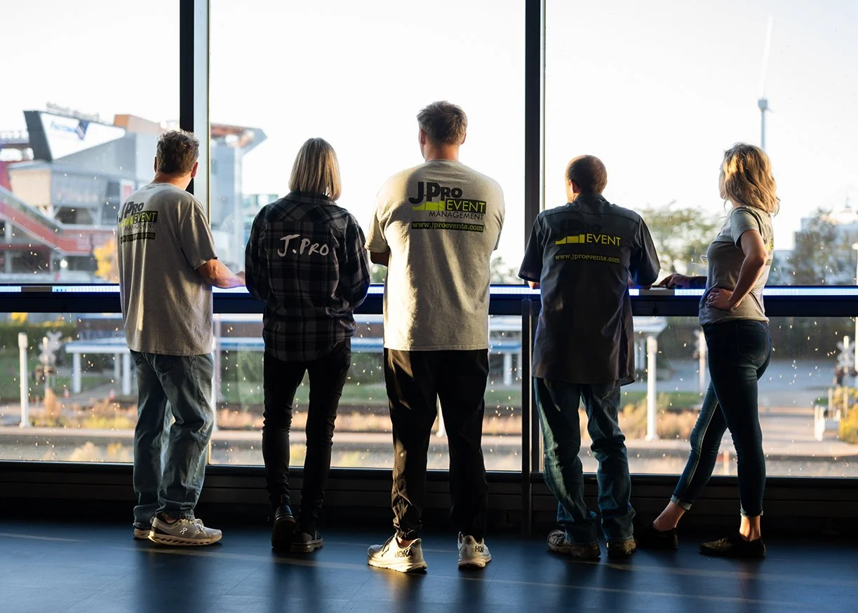Group of five people looking out large window at an urban landscape with bridges and buildings.