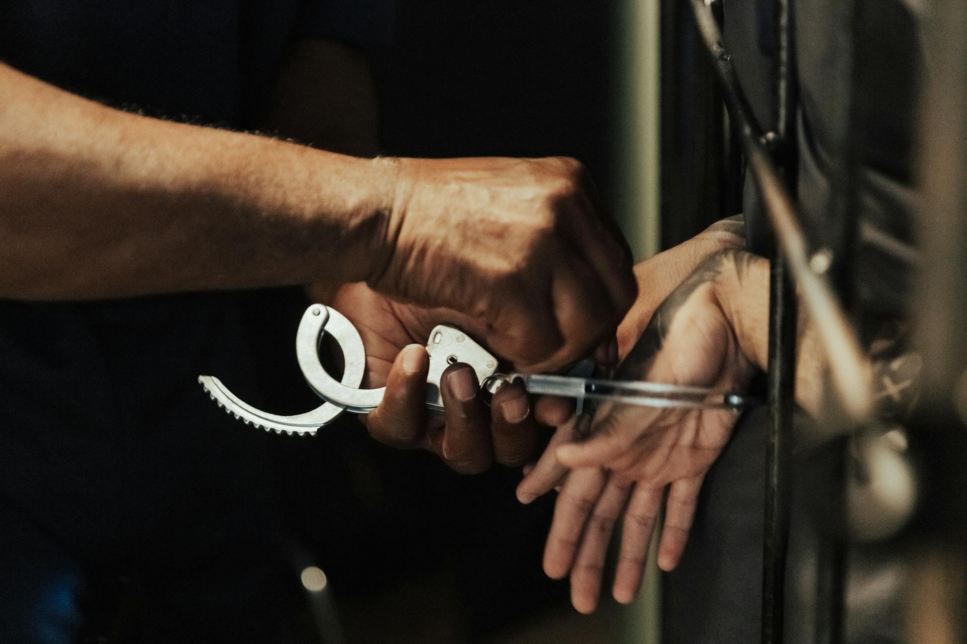 A person holding handcuffs while handcuffing another person's wrist.