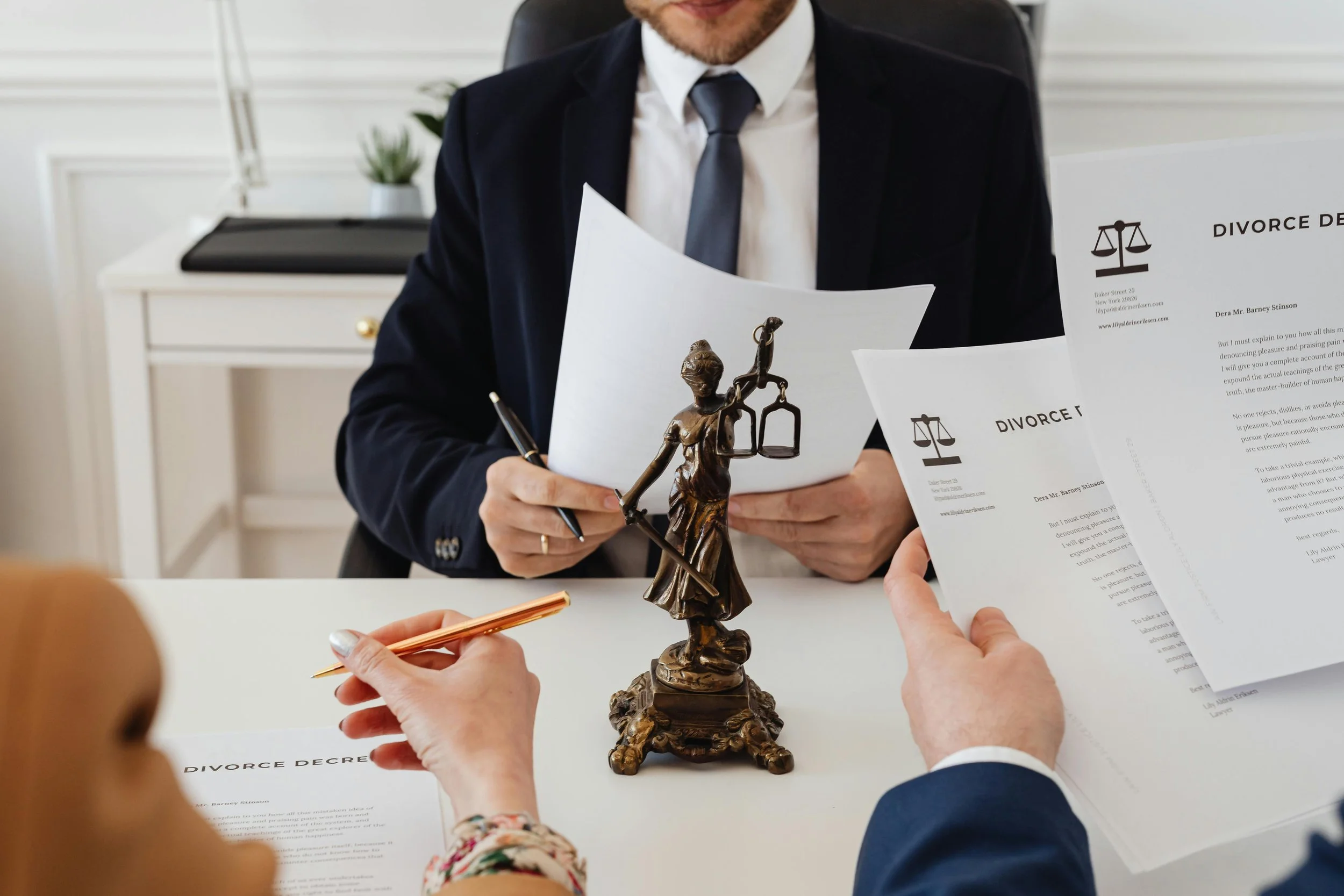 Legal professionals reviewing divorce decrees at a desk with a brass Lady Justice statue.