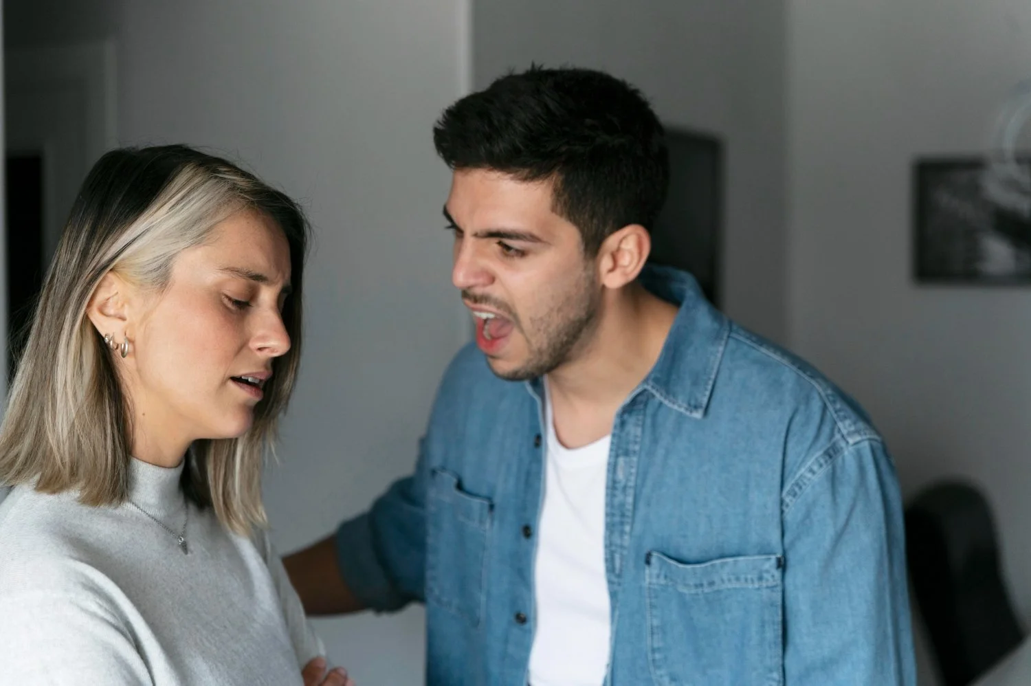 A man appears to be yelling or arguing at a woman, who has her eyes closed and looks upset.