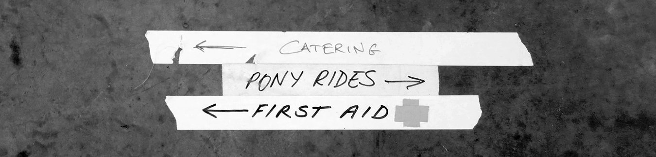 Handwritten signs with arrows pointing left or right, indicating directions for catering, pony rides, and first aid.