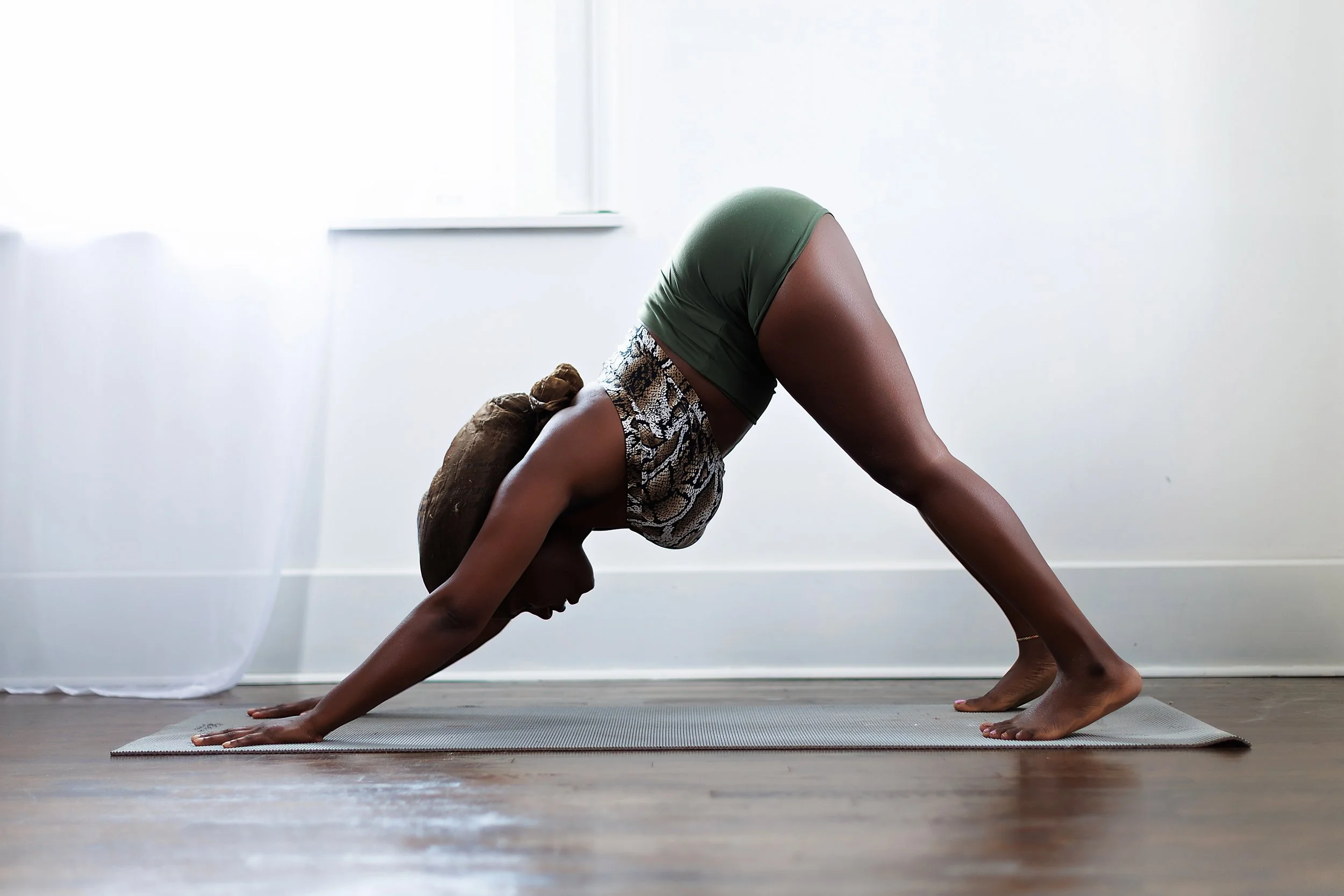Woman in varisara yoga pose on a yoga mat in a bright room.