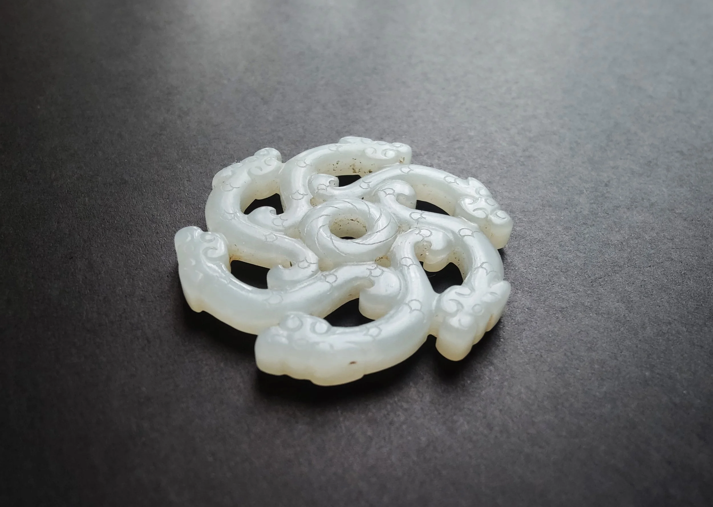 A Chinese white jade openwork pendant depicting chilong dragons