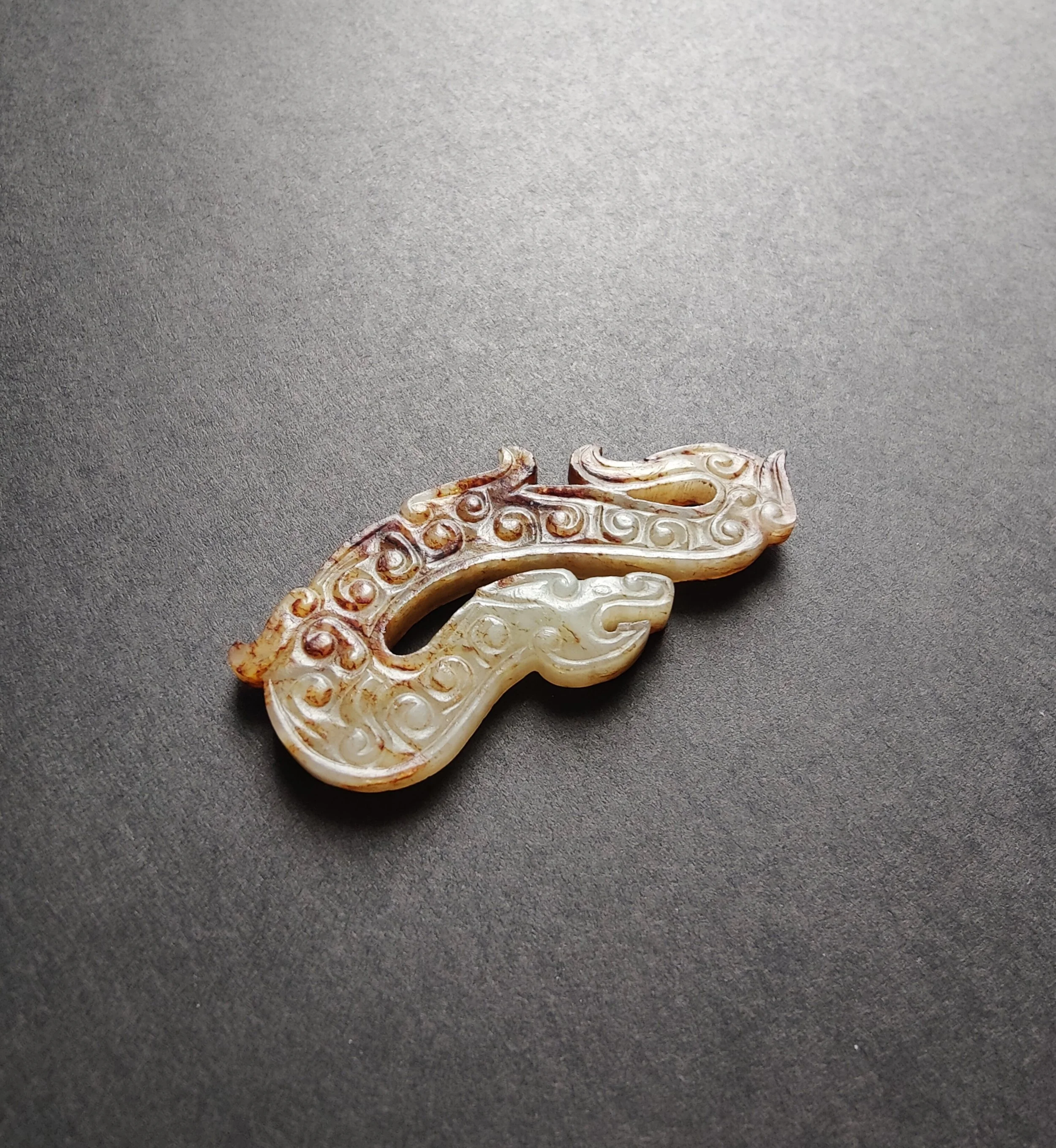 A Chinese Archaic Celadon and Russet Jade Dragon Pendant