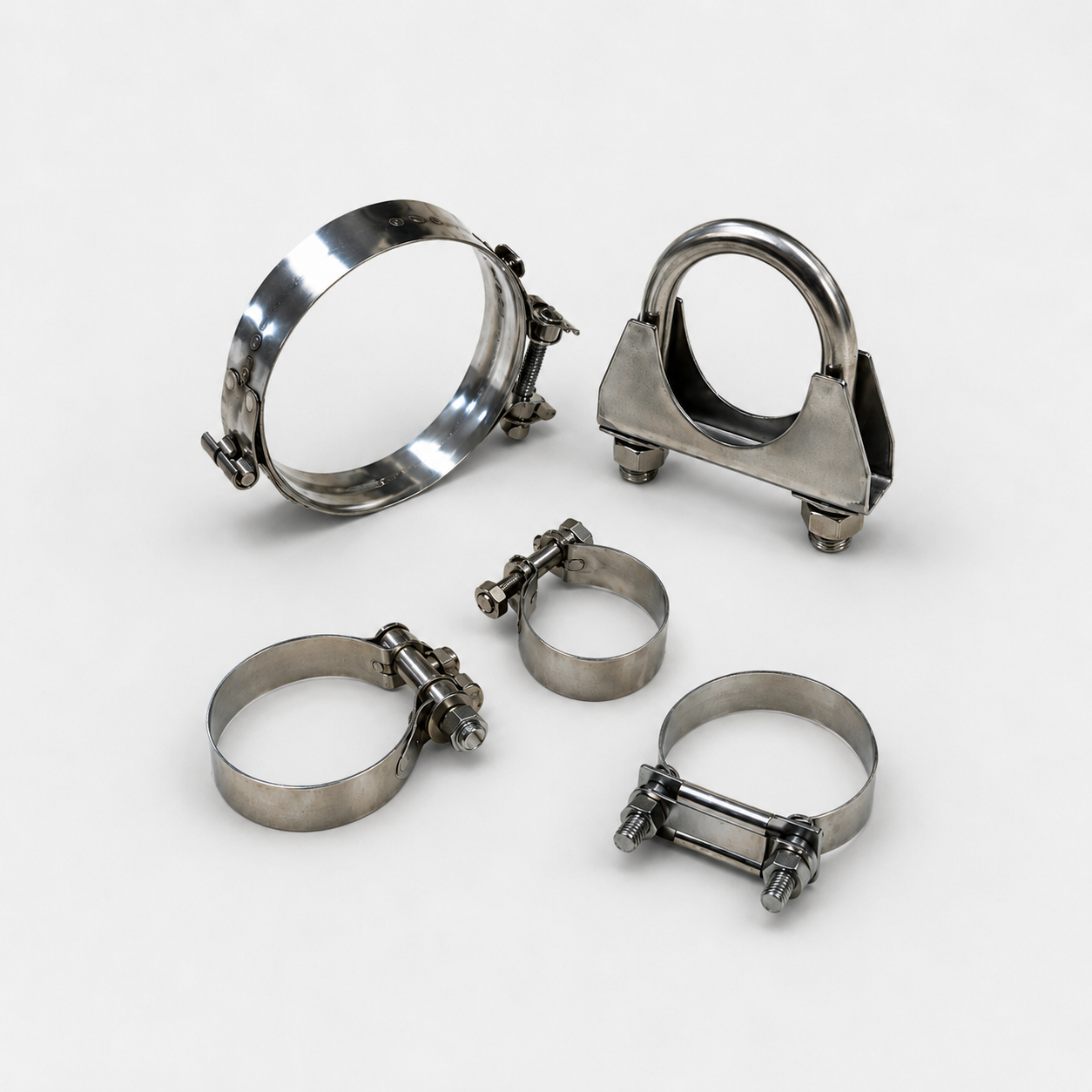 Various metal hose clamps and fittings arranged on a white surface.