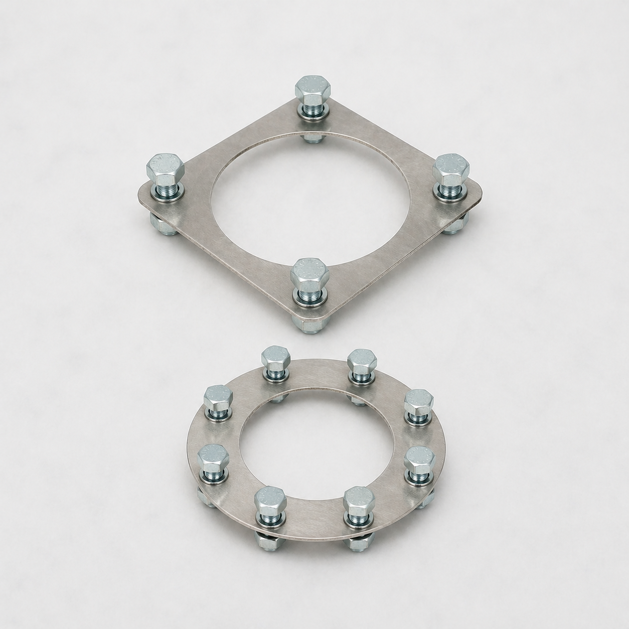 Two metallic circular mounting brackets with bolts, one larger and one smaller, placed on a white surface.