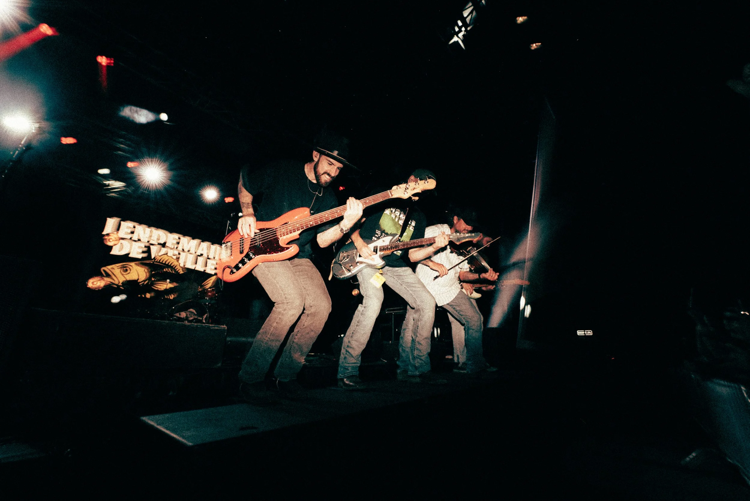 Groupe de musiciens jouant de la guitare et du violon sur scène lors d'un concert.